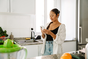 A woman is standing and typing on the phone