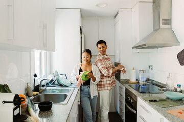 A man wipes his hands with a napkin while talking to a woman standing next to him and wiping the...