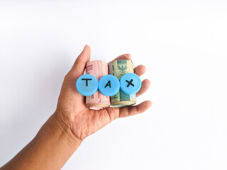 Rolled rupiah banknotes in the palm of the hand and the word tax written on it