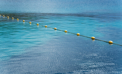 Yellow buoys on the surface of the turquoise sea, sea vacation in tropics and safety concept © olezzo