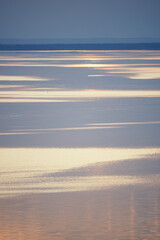 River landscape, illuminated areas on the water, sunset time, coastline.