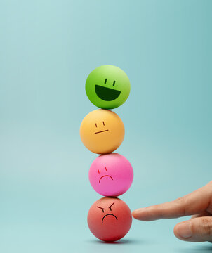 Hand balancing Colorful emotional faces Ball, symbolizing mental health and emotional