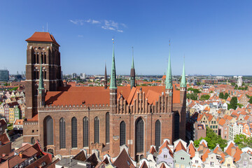 Aerial panoramic view of the historic Old Town of Gdask, Poland, with red tiled rooftops, bustling pedestrian street, and surrounding green landscape on a sunny summer day