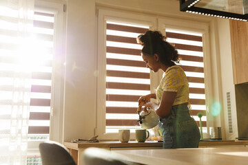 A female musician stands at the table and pours from a kettle into cups
