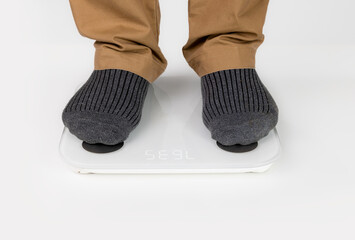 Senior man on scales indoors, close up. Weight gain.