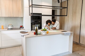 A father and his daughter are standing at a table and rolling out dough with a rolling pin