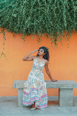 Obraz premium A woman is sitting on a bench wearing a colorful dress