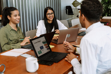 Obraz premium Two female employees are smiling and listening to a male employee sitting across from them at the table
