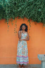 Fototapeta premium A woman is standing in front of a wall with a green plant growing on it