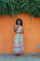 Fototapeta premium A woman in a white dress stands in front of a wall with green vines
