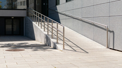 Modern building entrance with concrete ramp and metal handrails