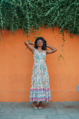 Obraz premium A woman in a long dress stands in front of a wall with green vines