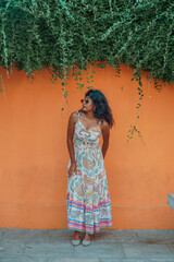 Fototapeta premium A woman in a long dress stands in front of a wall