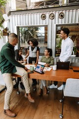 A group of five workers at a table laughing while one of them talks