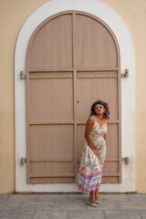 Fototapeta premium A woman in a dress stands in front of a building with a doorway