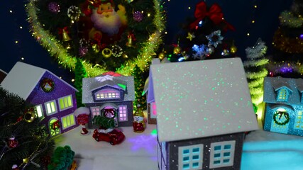 A close-up of a grey house spinning in front of a large decorated Christmas town