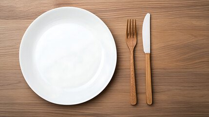 Elevated view of a white ceramic plate, wooden fork, and knife on a wooden table setting. Clean and minimalist dining arrangement. Classic table utensils.