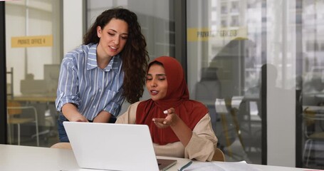 Positive diverse young female managers working at laptop together - Powered by Adobe