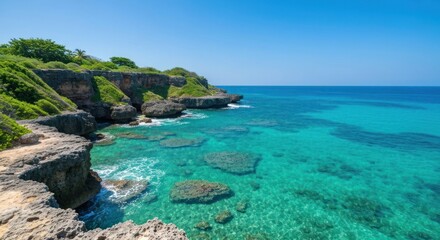 Sunny view of clear turquoise ocean water next to green-topped rocky cliffs