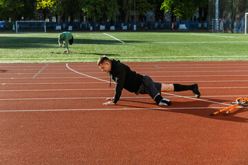 A man does push-ups while a man next to him picks up crutches
