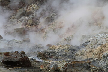 hot soil and stones in Seltun geothermal area with the sulfuric crystals and other minerals coloring the stones and steam coming off the surface