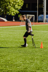 Obraz premium A man on crutches runs and dribbles a ball after a cone