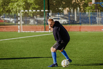 A man turns and looks at the ball next to him on the field