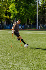 Obraz premium A man reaches for a ball that is dribbles across the field while running on crutches