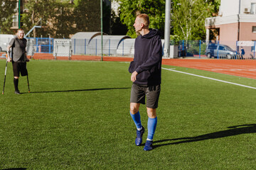 Fototapeta premium A male player walks and looks towards a male player who is leaning on crutches