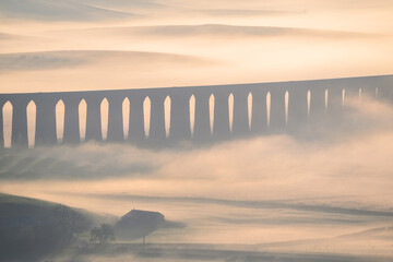 Aerial view looking down to The Ribblehead Viaduct as the morning fog lingers in the valley,...