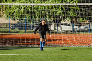 A male goalkeeper stands in the middle of the goal