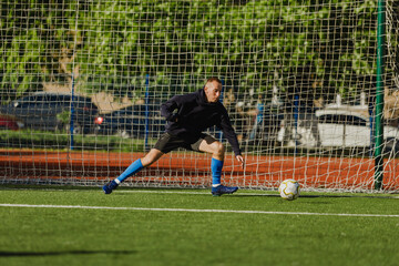 A man falls to the side to catch the ball near the goal