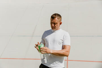 A man looks at the bottle he is holding