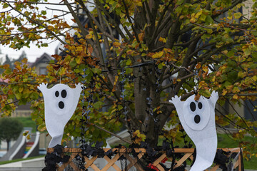 Ghost halloween decoration hanging on the tree. Festive Halloween decor scene