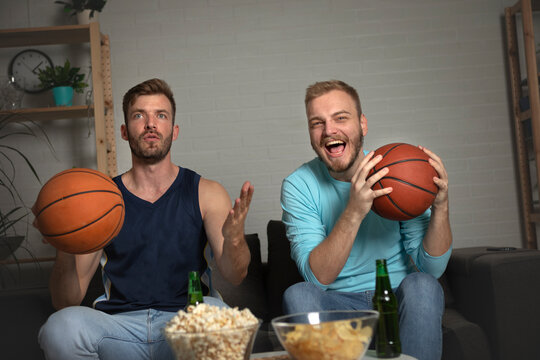 Two diverse male friends watching game on tv