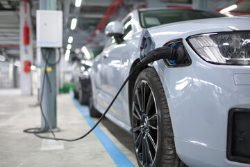 Naklejka premium Charging an electric car with the power cable supply plugged in.