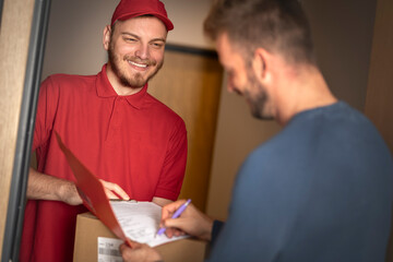 Young man signing a package with courier.
