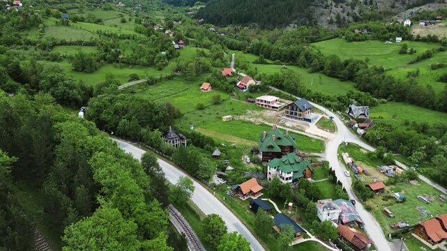Retro tourist train Sargan Eight winding through the lush green hills near Mokra Gora village in Serbia, seen from above. Horizontal aerial view - 4k footage