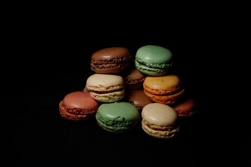 Assortment of colorful macarons arranged on a dark background. French almond cookies with different...