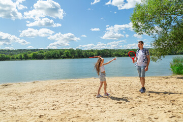 Father and daughter having fun on the beach during summer vacation playing beach tennis