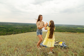 Mother with daughter blowing soap bubbles in field on summer day