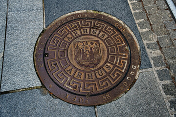 Kanaldeckel der Stadt Arhus in Dänemark mit symbolisierten Wahrzeichen der Stadt