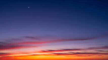 Obraz premium Vibrant sunset sky with distant moon and clouds