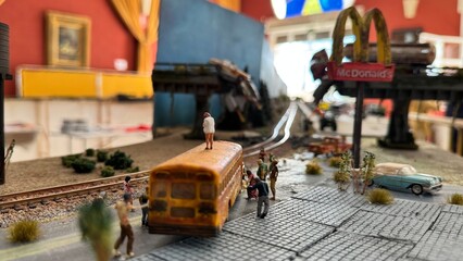 Detailed posaocaliptic zombie miniature urban diorama with school bus, pedestrians, and train tracks creating a realistic small-scale city scene