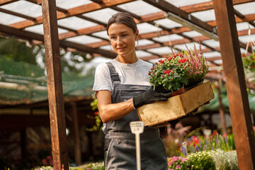 A woman tending to colorful flowers in a flourishing greenhouse, showcasing her passion for...