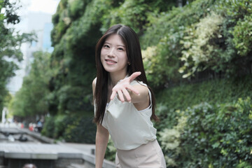 Fototapeta premium 豊かな緑を背景に立つ、爽やかでエレガントなアジア人女性のポートレート。健康、サステナビリティ、リフレッシュ、そして明るい未来を象徴するイメージ素材、エコロジーや企業CSR広告に最適