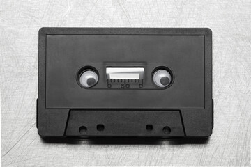 Obraz premium Retro acoustic. Funny black Audio cassette tape on a metallic background. Vintage media concept. TOP VIEW