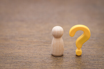 A simple wooden peg doll with a yellow question mark symbolizes the universal human experiences of...
