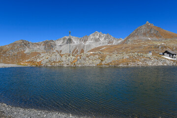 High mountain panorama in late summer, early autumn, with green and yellow larches, blue sky, in the Swiss Alps.