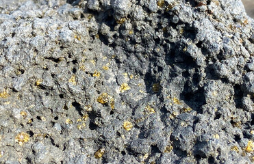 Olivine gemstones included in black lava basalt rock in Tenerife,Canary Islands,Spain.Peridot crystals. Selective focus.
